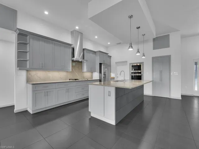 Kitchen featuring a sink, wall chimney range hood, gray cabinets, appliances with stainless steel finishes, and open shelves