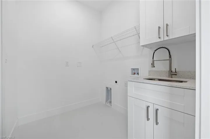 Laundry room with cabinet space, hookup for a washing machine, electric dryer hookup, and finished concrete flooring