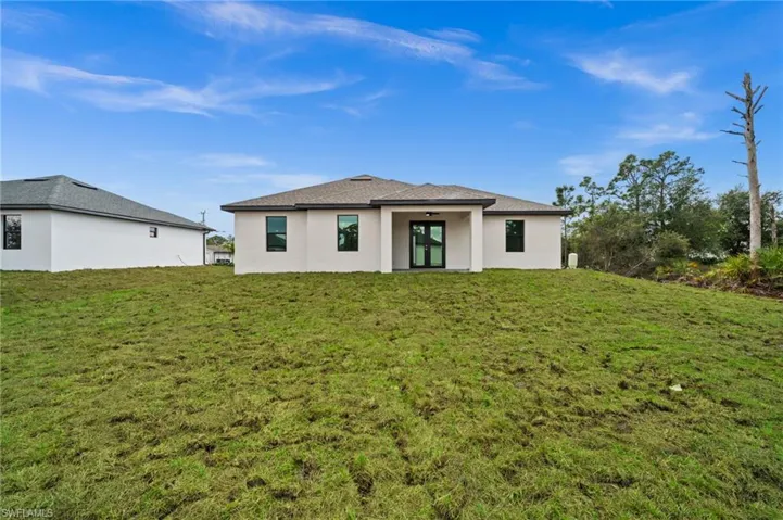 Rear view of house featuring stucco siding and a lawn