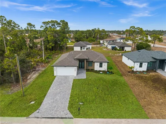 View of front facade with decorative driveway, a front lawn, an attached garage, and a residential view