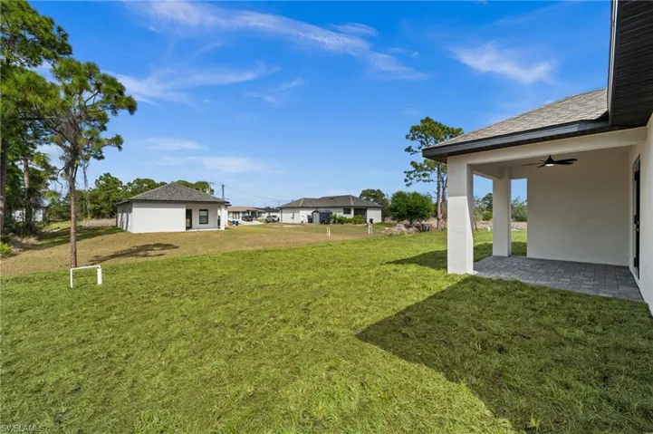View of green lawn with ceiling fan and a patio