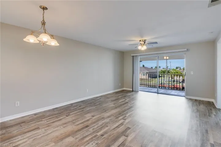 Spare room with wood finished floors, a chandelier, and a ceiling fan