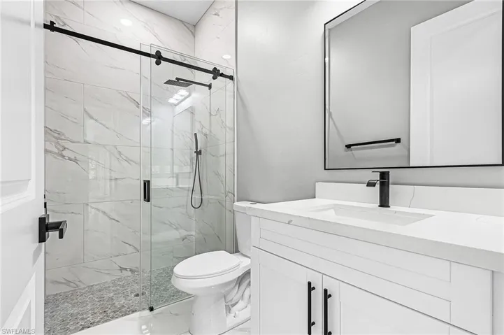 Bathroom with vanity, a marble finish shower, and porcelain tile flooring