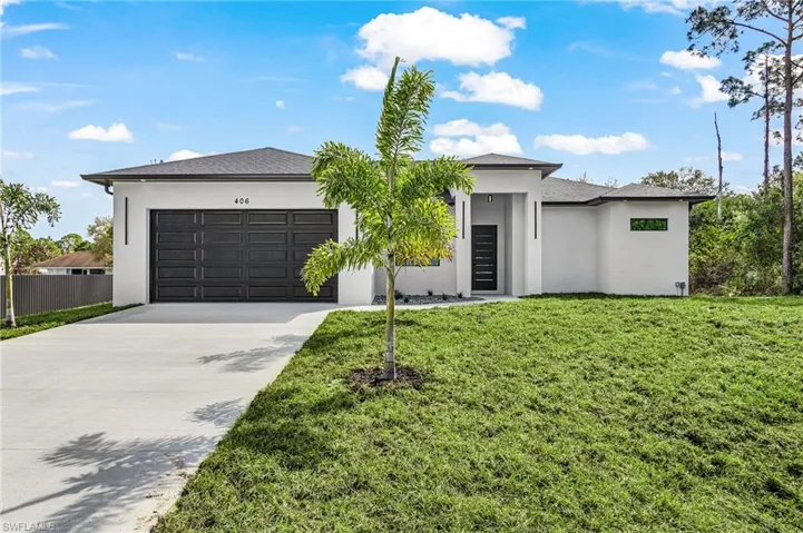 Prairie-style home with stucco siding, driveway, an attached garage, and a front yard