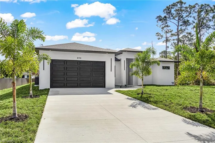 Prairie-style home featuring a front yard, driveway, an attached garage, and stucco siding