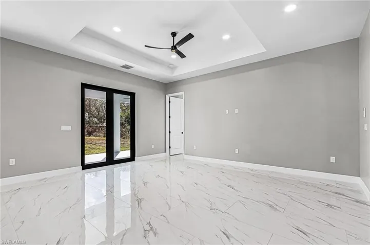 Empty room with ceiling fan, light porcelain finish floors, a tray ceiling, and recessed lighting