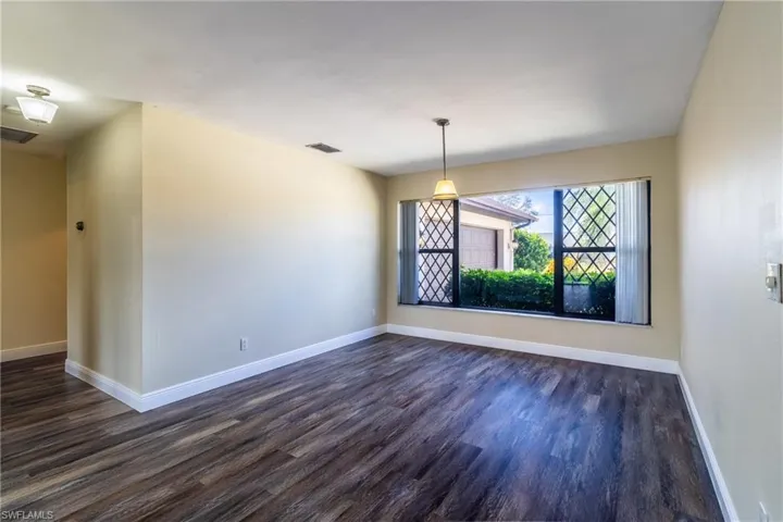 Unfurnished dining area featuring baseboards and dark wood-style flooring