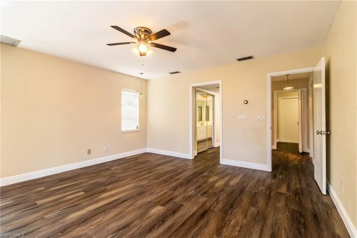 Unfurnished bedroom featuring dark wood-style floors, a ceiling fan, and ensuite bathroom