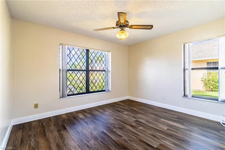 Spare room with dark wood-style floors, ceiling fan, and a textured ceiling