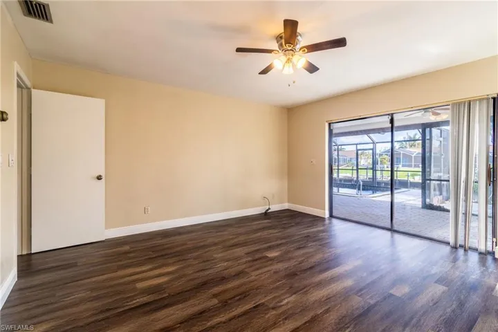 Unfurnished room with ceiling fan, dark wood-style flooring, and a sunroom