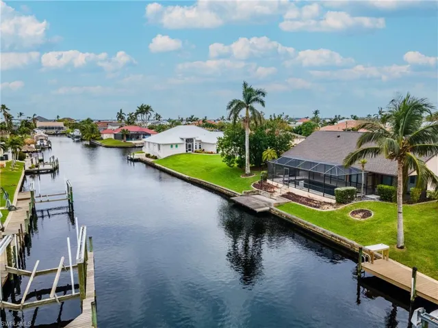 Dock area with a water view, a residential view, boat lift, a sunroom, and a patio