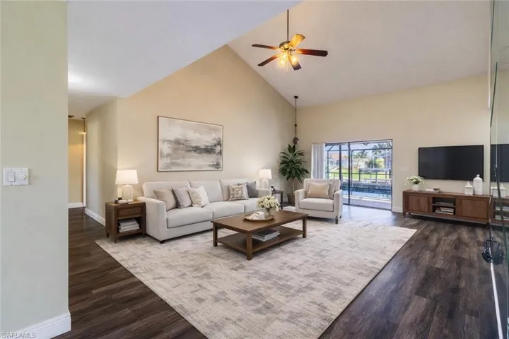 VIRTUALLY STAGED! Living area featuring a ceiling fan, dark wood-style floors, and lofted ceiling
