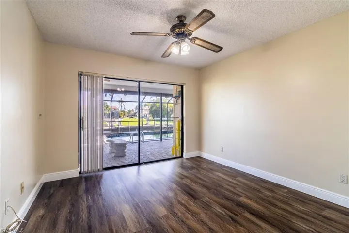Unfurnished room featuring dark wood-style floors, ceiling fan, and a textured ceiling