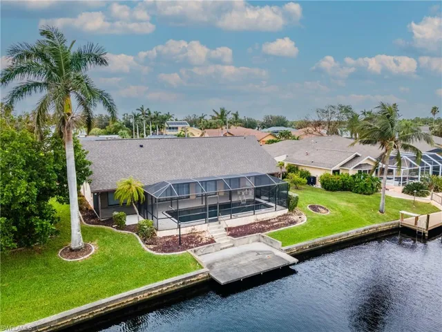 Back of house with a sunroom, a lanai, a lawn, a water view, and a shingled roof