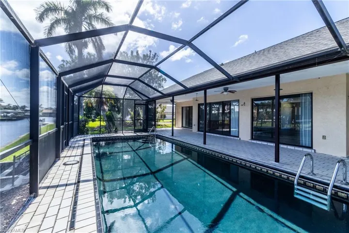 Swimming pool with glass enclosure, a sunroom, and a patio