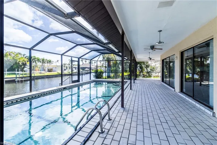 Outdoor pool featuring a sunroom, a patio, a water view, and a lanai