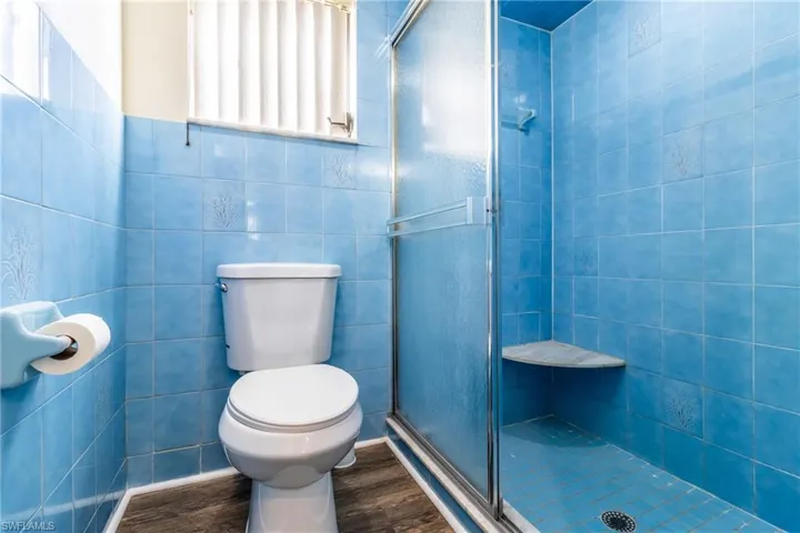 Full bath with a stall shower, tile walls, and wood finished floors