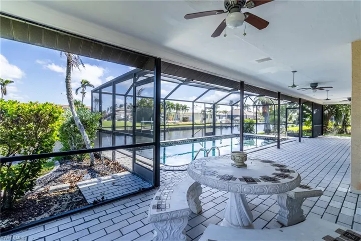 Swimming pool with a sunroom, glass enclosure, a water view, and a patio