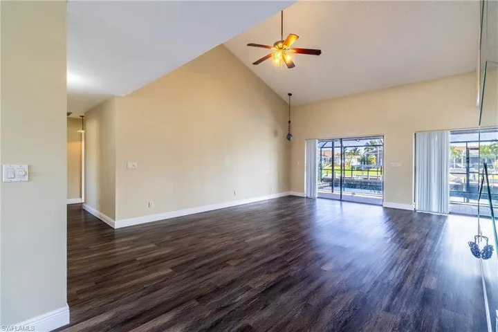 Empty room featuring ceiling fan, lofted ceiling, and dark wood finished floors