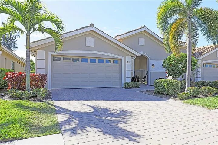 View of front facade featuring decorative driveway, a garage, stucco siding, and a gate
