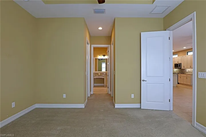Unfurnished bedroom featuring light carpet, recessed lighting, ensuite bathroom, and light tile patterned floors