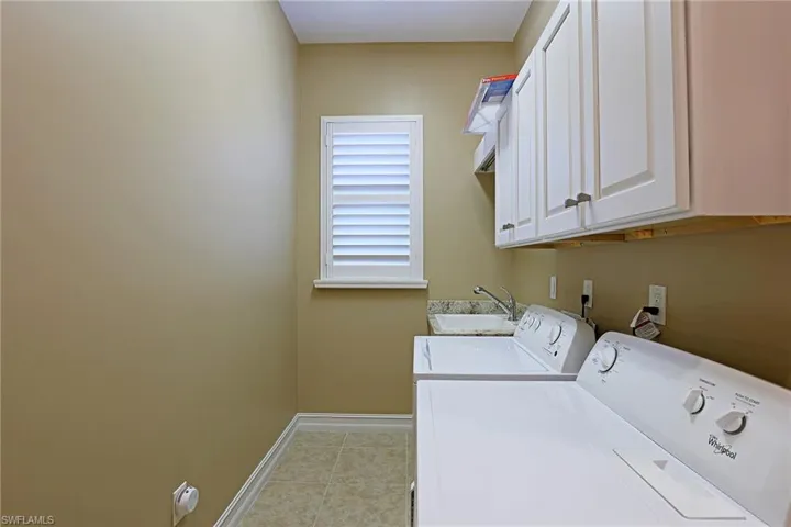 Laundry room featuring washer and clothes dryer, cabinet space, and light tile patterned flooring