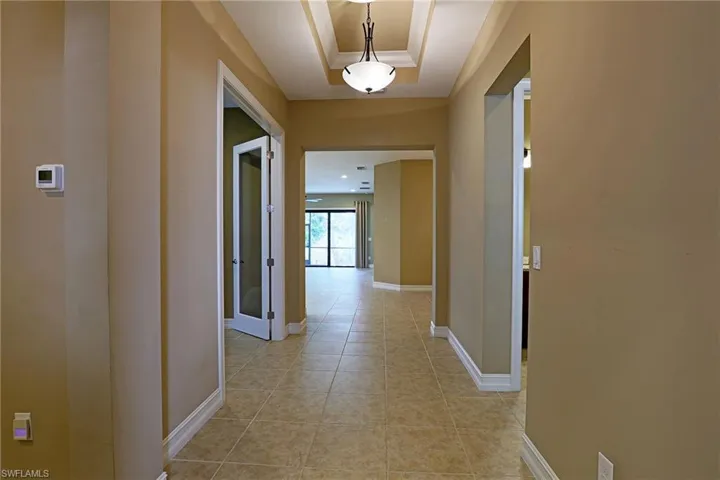 Hall featuring a raised ceiling and light tile patterned floors
