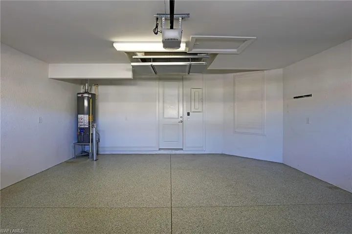 Garage with gas water heater, a garage door opener, and electric panel