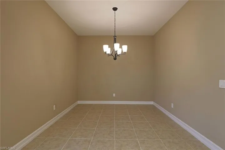 Empty room with suspended lighting and light tile patterned floors