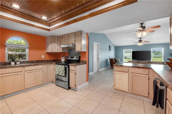 Kitchen with light brown cabinetry, dark countertops, stainless steel appliances, ceiling fan, and recessed lighting