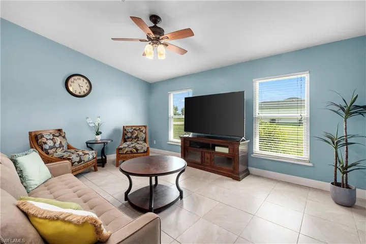 Living room featuring light tile patterned floors, ceiling fan, and vaulted ceiling
