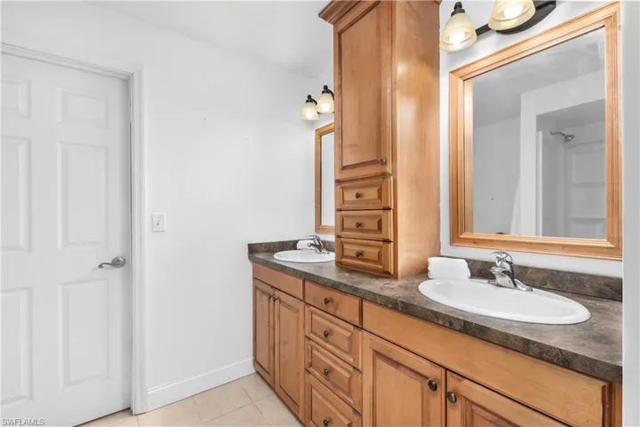 Full bath featuring light tile patterned floors and double vanity