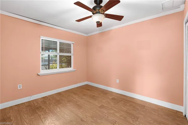 Empty room with ornamental molding, light wood finished floors, and a ceiling fan
