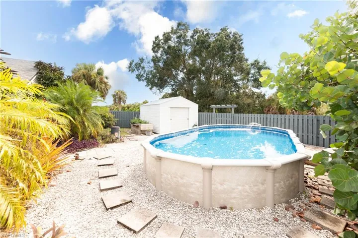 View of swimming pool featuring a fenced backyard, a patio, and a storage unit