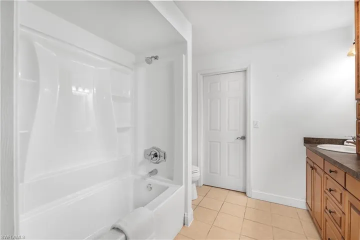 Full bath featuring light tile patterned floors, vanity, and tub / shower combination