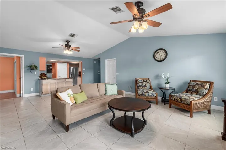 Living room with a ceiling fan, vaulted ceiling, and light tile patterned flooring