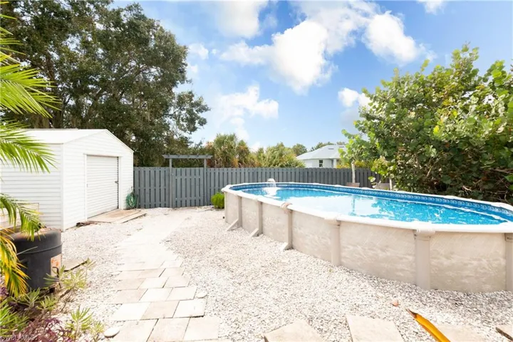 View of swimming pool featuring a storage unit, a patio area, and a fenced backyard