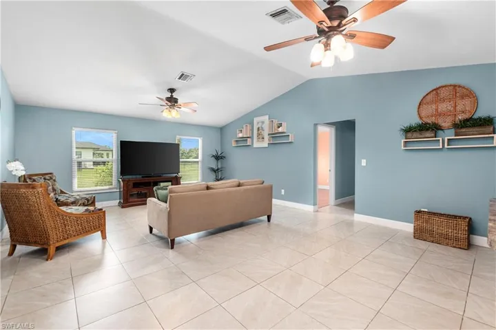 Living room with light tile patterned floors, ceiling fan, and vaulted ceiling