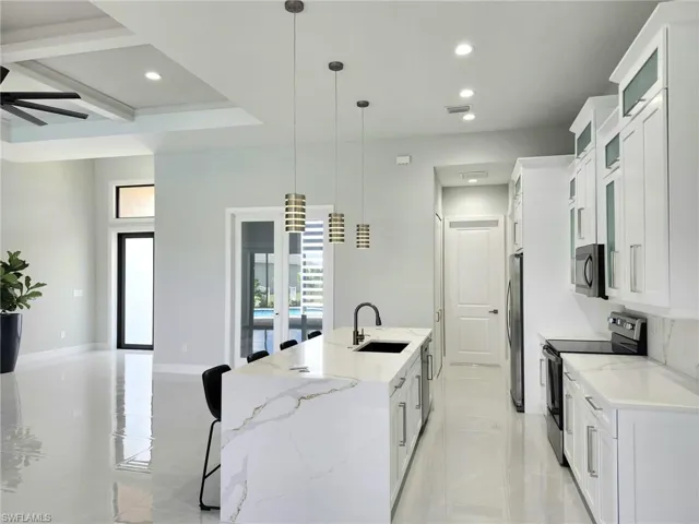 Kitchen featuring sink, a spacious island, white cabinetry, appliances with stainless steel finishes, and ceiling fan
