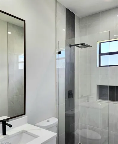 Bathroom featuring a shower with shower door, toilet, and vanity