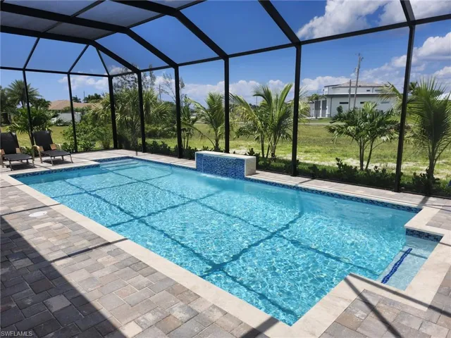 View of swimming pool featuring glass enclosure, pool water feature, and a patio