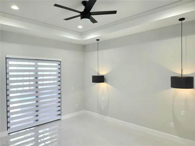 Unfurnished room featuring ceiling fan and a raised ceiling