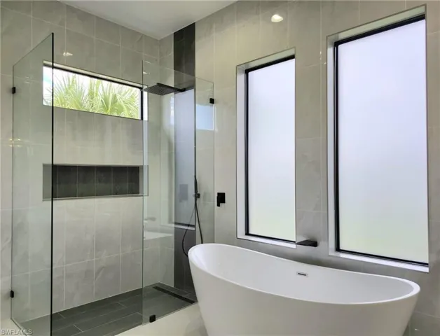 Bathroom featuring plus walk in shower and tile walls