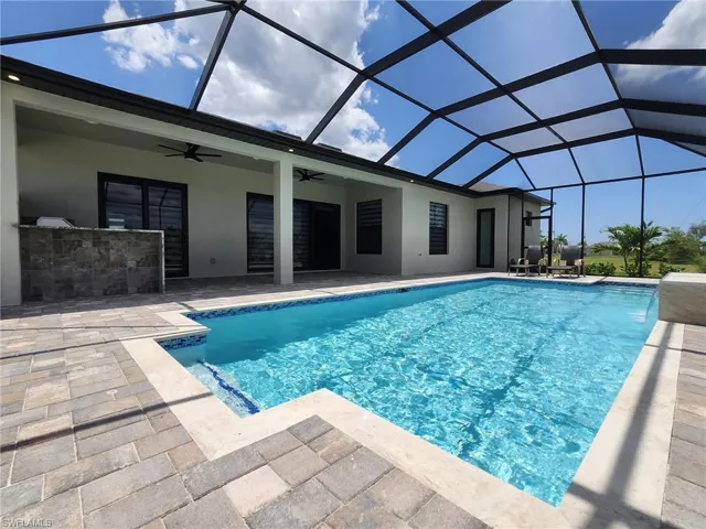 View of pool featuring glass enclosure, ceiling fan, and a patio