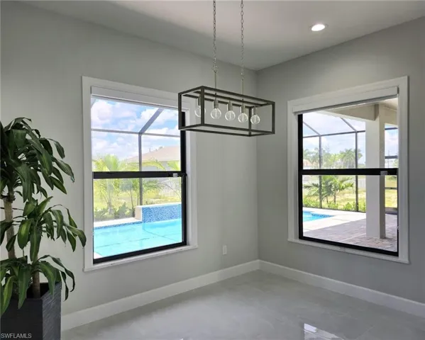 Unfurnished dining area featuring an inviting chandelier, tile patterned floors, and a healthy amount of sunlight