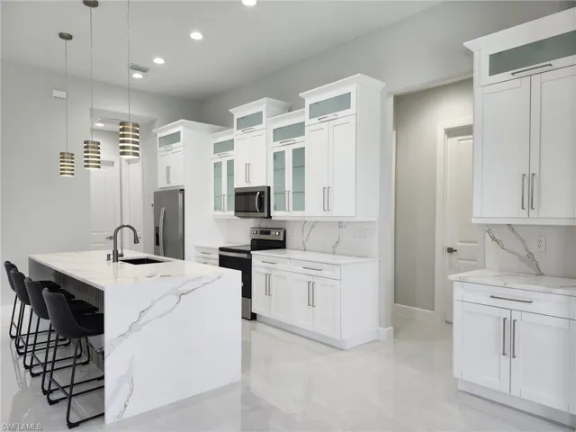 Kitchen featuring backsplash, light stone countertops, sink, a center island with sink, and stainless steel appliances