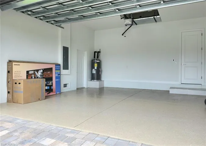 Garage with a garage door opener, electric water heater, and electric panel