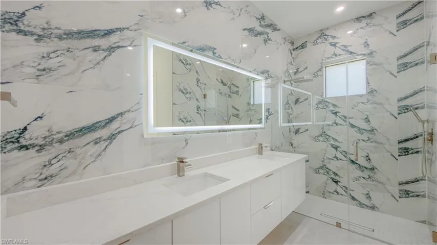 Bathroom with double vanity, a marble finish shower, and recessed lighting