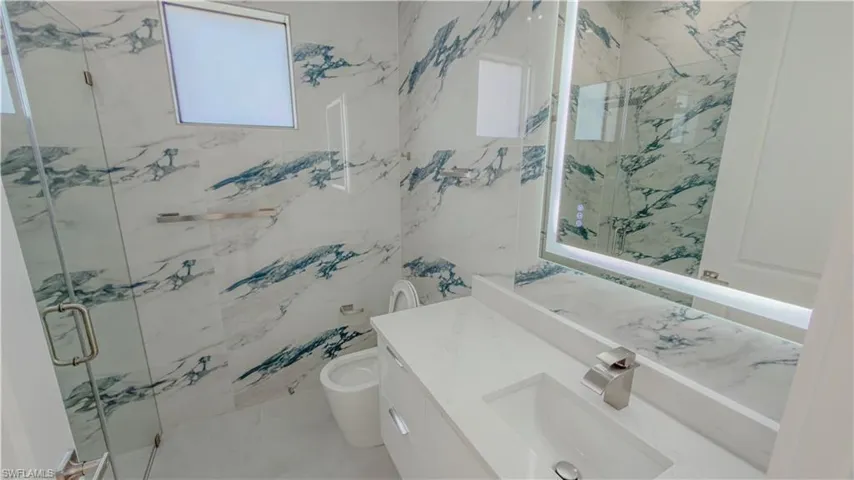 Bathroom featuring vanity, a marble finish shower, and plenty of natural light