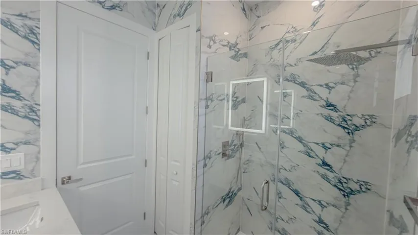 Bathroom featuring vanity and a marble finish shower